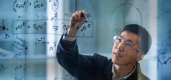Scientist writing calculations on glass wall